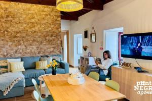 una donna seduta in un soggiorno con TV di Charming Country House by Ponta Negra Azores a Altares