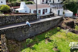 un uomo seduto su un muro vicino a una casa di Charming Country House by Ponta Negra Azores a Altares