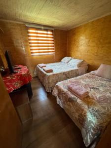 ビクーニャにあるHabitación en Cabaña compartidaのベッド2台とテーブルと窓のある寝室