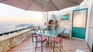 a balcony with a glass table and chairs at Epic 180 degree Sea & 3 Island Views Sun Terrace Penthouse in Qala
