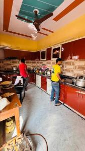 two men standing in a kitchen preparing food at Bhiwani Guest House in Jaipur