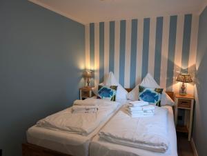 a bedroom with two beds with white sheets and pillows at Schmucke-Huus-Bungalow in Westerland (Sylt)