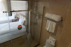 a bathroom with a shower with a toilet and towels at GreenTree Inn Datong Railway Station South Yundingyayuan Express Hotel in Datong