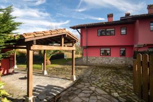 La Pereda de LlanesにあるMirador sierra del cueraの赤い家の前の木造パビリオン