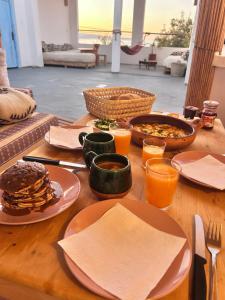a wooden table with plates of food and glasses of orange juice at Sun & Sea Lodge Ocean roof in Essaouira
