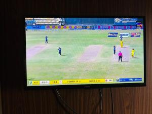 a television screen showing a cricket game on a field at Dun Haven Height in Dehradun