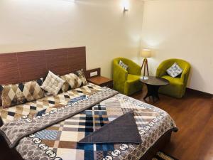 a bedroom with a bed and two green chairs at Dun Haven Height in Dehradun
