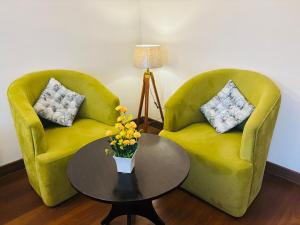 two green chairs and a table with a vase of flowers at Dun Haven Height in Dehradun