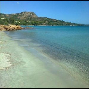 una playa con agua azul y montañas de fondo en Casa Turchese, en Olbia 4 fotos más