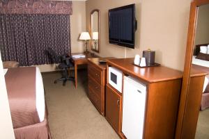 a hotel room with a bed and a desk with a television at Heartland Inn Hotel and Suites in Park Rapids