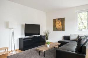 a living room with a black couch and a flat screen tv at BASELiving 3,5 Room Apartment - Bahnhof Basel SBB - Self Check-in in Basel