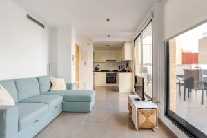 a living room with a blue couch and a kitchen at Apartamento Sunshine Grao in Burriana
