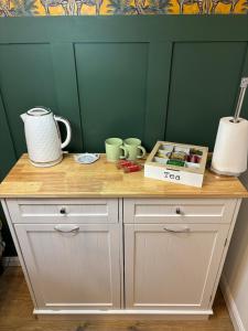 a wooden counter with cups and mugs on it at Cosy Studio Near Park and Town in Bromsgrove +4 photos