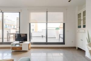 a living room with large windows and a tv at Apartamento Sunshine Grao in Burriana