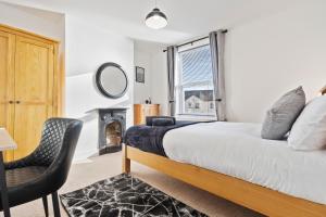 a bedroom with a bed and a chair and a window at Wolverhampton Townhouse - 3BR - Business & Leisure guests in Wolverhampton