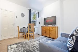 a living room with a couch and a tv and a table at Wolverhampton Townhouse - 3BR - Business & Leisure guests in Wolverhampton