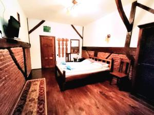 a bedroom with a bed in a room with wooden floors at Pensiunea Cerbul - Valea Dobârlăului in Valea Dobîrlăului
