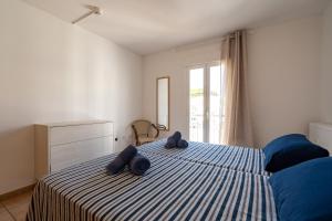 a bedroom with a bed with two blue towels on it at Apartamentos S'Avaradero in Es Pujols