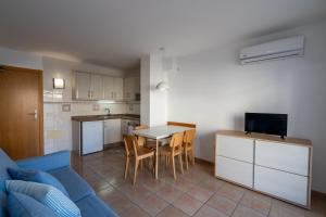a living room with a blue couch and a kitchen at Apartamentos S'Avaradero in Es Pujols