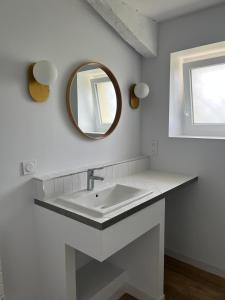 a white bathroom with a sink and a mirror at La maison du pin in Les Salles-de-Castillon