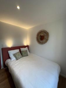 a bedroom with a white bed with a mirror on the wall at La maison du pin in Les Salles-de-Castillon