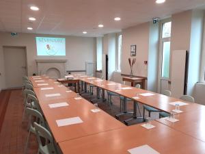 GétignéにあるVillage de Gîtes du Moulin Neufのテーブルと椅子、プレゼンテーションが備わる広い客室です。