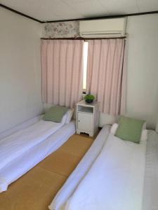 two beds in a small room with a window at Nippori Osaka Nishi-Tengachaya Guesthouse西天下茶屋アパートメント in Osaka
