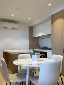a kitchen with a white table and chairs at Box Hill luxury 29th floor apartment with car park in Box Hill