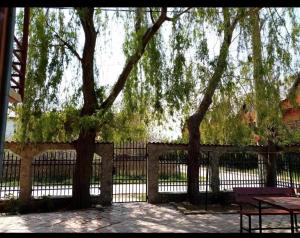 a fence with trees and a table and a bench at Vila Masy in Costinesti
