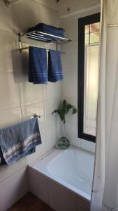 a white bathroom with blue towels and a window at Aire de campo en la ciudad in San Fernando del Valle de Catamarca