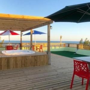 a wooden deck with a hot tub and an umbrella at Residencial Veleiros Do Mar in Capão da Canoa