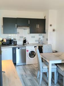 a kitchen with a washing machine and a table with chairs at Cosy appartement dans une villa avec piscine, proche du centre et de la mer in Cabourg