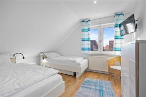 ein weißes Schlafzimmer mit einem Bett und einem Fenster in der Unterkunft Ferienhaus Kristina in Hooksiel