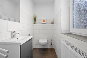 ein weißes Badezimmer mit Toilette und Waschbecken in der Unterkunft Ferienhaus Kristina in Hooksiel