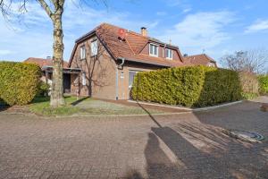 ein Haus mit einem Baum und einer steinernen Einfahrt in der Unterkunft Ferienhaus Kristina in Hooksiel + 2 Fotos