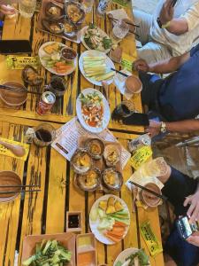 a group of people sitting around a wooden table with food at Homestay Hoàng Phúc in Cu Lao Thu