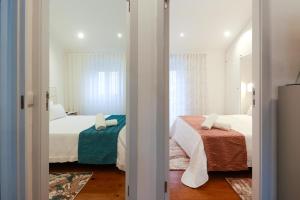 a bedroom with two beds and a window at Guest House Abegorias Nazaré in Nazaré