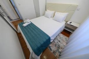 a small bedroom with a bed with a green blanket at Guest House Abegorias Nazaré in Nazaré