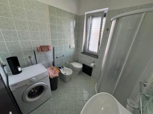 a bathroom with a washing machine and a toilet at CASA VACANZA BORGOROSSO A 70mt DAL MARE in Casa Borgorosso +7 photos