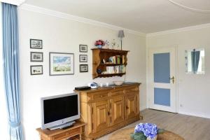 una sala de estar con TV en un centro de entretenimiento de madera en Gartenstr. 2F, en Westerland