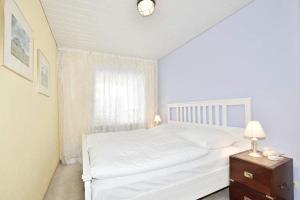Dormitorio blanco con cama blanca y mesa en Gartenstr. 2F, en Westerland