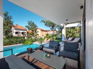 a patio with a table and chairs and a swimming pool at Casa Dea in Malinska
