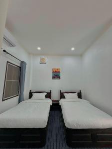 two twin beds in a small room withermottermottermott at Utopia house-luang prabang琅勃拉邦乌托邦庭院 in Luang Prabang