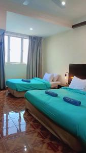 two beds in a room with blue sheets on them at Jev Penthouse in Port Dickson