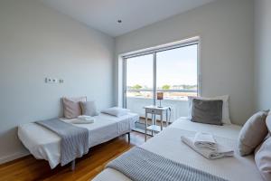 a white room with two beds and a window at Sunset Guest House in Matosinhos