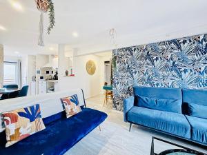 a living room with a blue couch and a kitchen at Suite Isaac - Appartement d'exception in Bray-Dunes