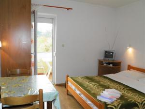a bedroom with a bed and a table and a television at Apartments Miljenka in Baška