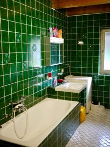 a green tiled bathroom with a tub and a sink at Großzügige Familienunterkunft in absoluter Idylle in Kiefersfelden