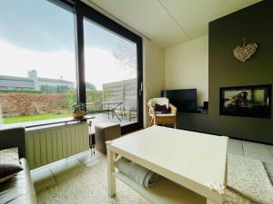 a living room with a white table and a large window at Heggerank 5B* in Nieuwvliet