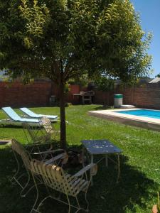 un tavolo e sedie sotto un albero accanto a una piscina di Mic-Bau a Villa Elisa